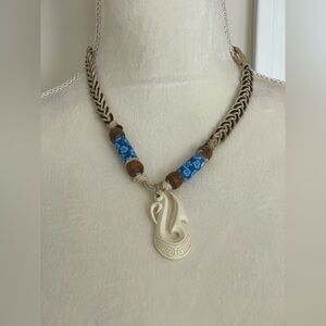 Woven medallion cord beach necklace with wooden beads accents sea horse pendant.